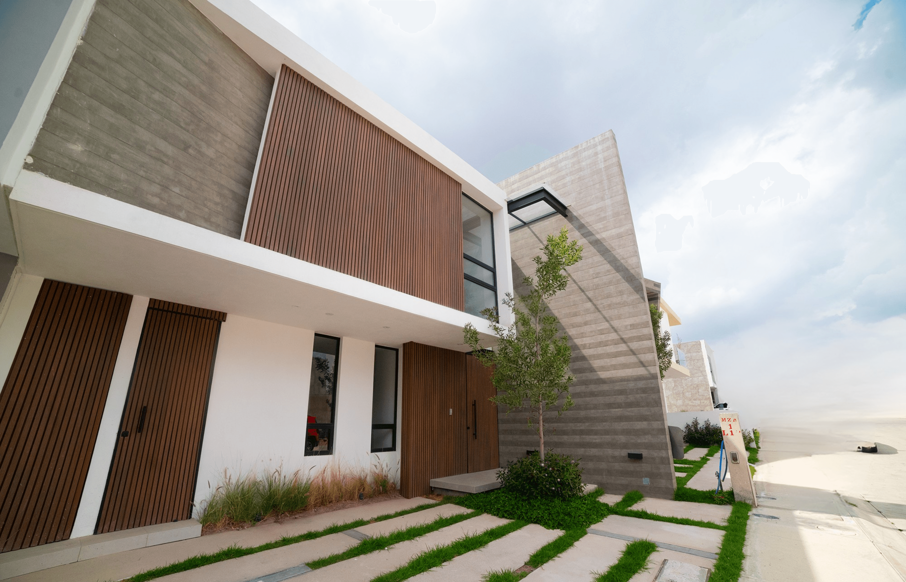 Casa residencial moderna de dos pisos con fachada blanca, madera y concreto en Pachuca, Hidalgo.